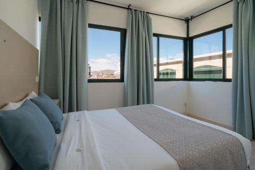 1 dormitorio con 1 cama y 2 ventanas en Sabbia Suites Arrecifeando, en Arrecife