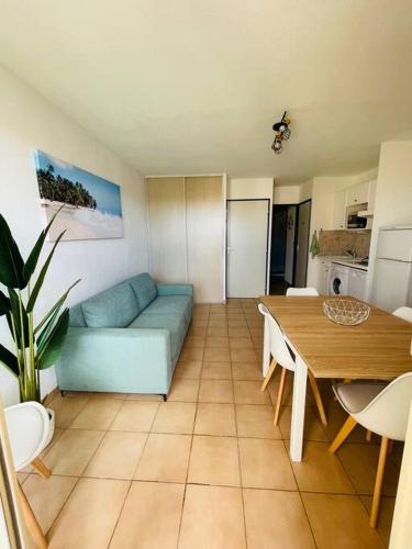 un salon avec un canapé bleu et une table dans l'établissement Appartement Sainte Marie la mer 66470, à Sainte-Marie-la-Mer