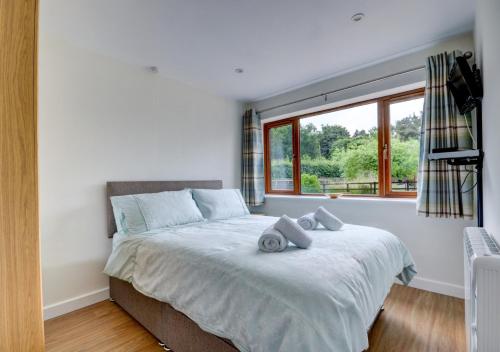 a bedroom with a large bed with a window at Acorn Cottage in Briston