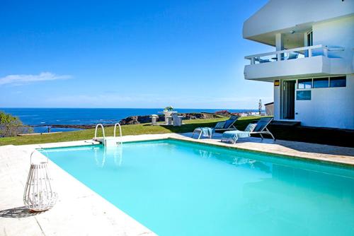 a swimming pool with two chairs and a house at Wishome-Villa sobre el mar en Comillas, con piscina in Comillas