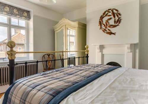 Albert Cottage في هولت: غرفة نوم بسرير ومدفأة