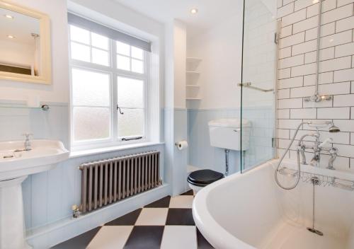 a bathroom with a tub and a sink and a window at Albert Cottage in Holt