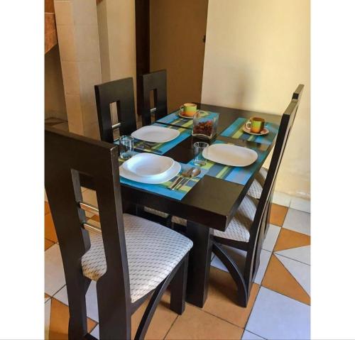 uma mesa preta com cadeiras e pratos em Bonita casa acogedora em Cochabamba