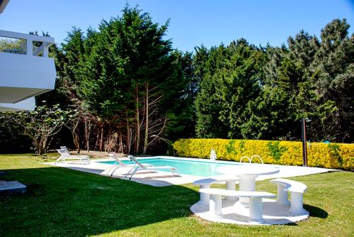 a swimming pool with two white benches next to it at Impresionante villa sobre el mar en el mismo Comillas in Comillas