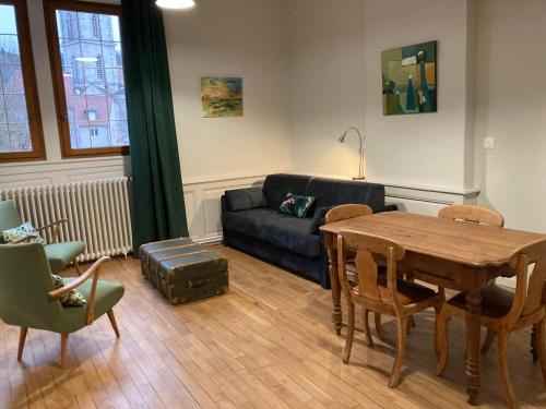 a living room with a table and a couch at Maison La Tourelle in Baume-les-Dames