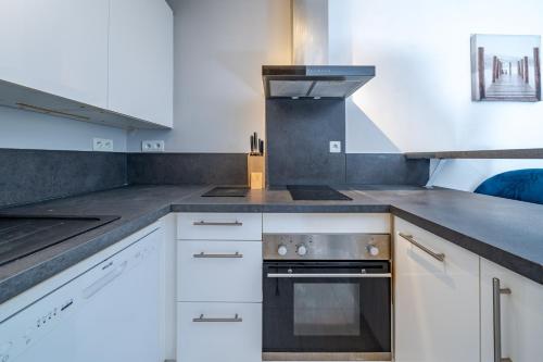 une cuisine avec des armoires blanches et un four à plaques de cuisson dans l'établissement Charmant appartement proche gare, à Nice