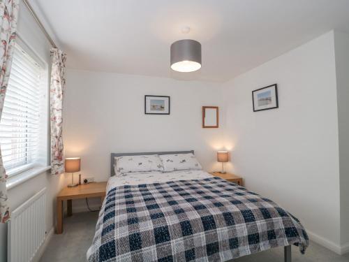 a bedroom with a bed with a checkered blanket at Covert Cottage in Axminster
