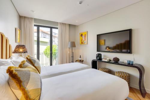 a bedroom with two beds and a flat screen tv at Portie Deluxe Suites by DA'HOME in Porto
