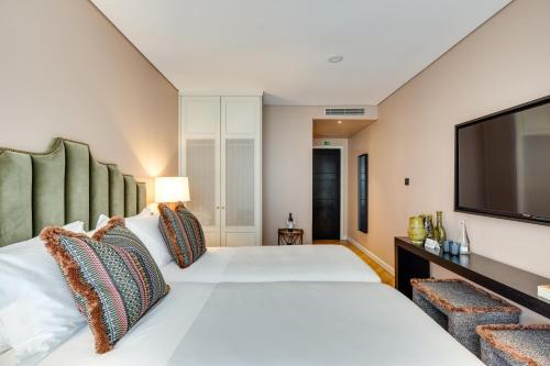 a bedroom with two beds and a flat screen tv at Portie Deluxe Suites by DA'HOME in Porto