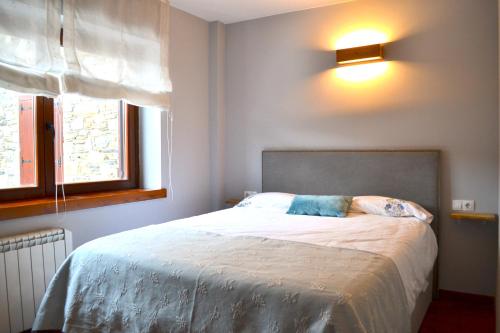 a bedroom with a bed and a light on the wall at Apartament rústic amb llar de foc by RURAL D'ÀNEU in Valencia de Aneu