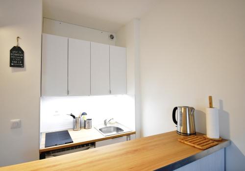 une cuisine avec des armoires blanches et un comptoir en bois dans l'établissement Balcons du port - Capbreton - A proximite immédiate du port de plaisance, studio en rez de chaussée avec cour dans résidence, à Capbreton