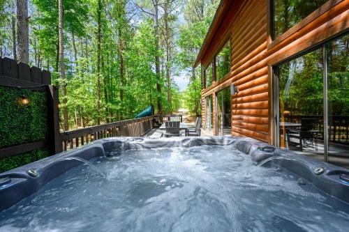 a hot tub on the back of a house at Hickory Bear - Cabin surrounded by pines, Sleeps 10, Hot Tub, Fire Pit, Arcade, Foosball Table & Deck Slide in Broken Bow