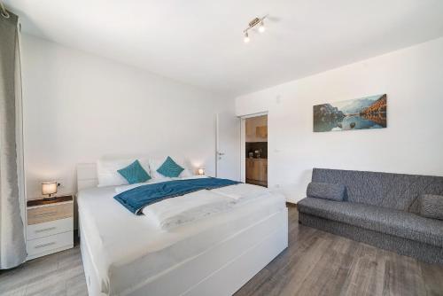 ein weißes Schlafzimmer mit einem Bett und einem Sofa in der Unterkunft Haus Tanja Apartment 1 in Partschins
