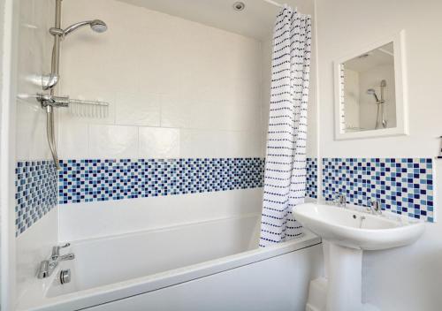 Beachcomber Cottage في هونستنتون: حمام مع حوض أبيض ومغسلة ومرحاض