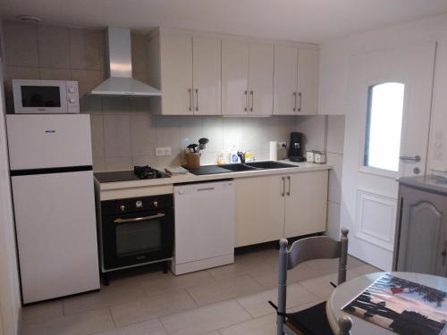 une cuisine avec des armoires blanches et un réfrigérateur blanc dans l'établissement gîte des Caves, à Civray-de-Touraine