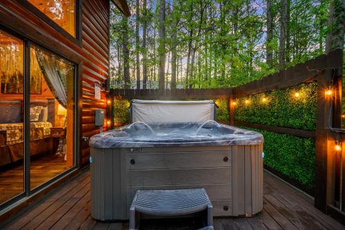 a jacuzzi tub on a deck with trees in the background at Hickory Bear - Cabin surrounded by pines, Sleeps 10, Hot Tub, Fire Pit, Arcade, Foosball Table & Deck Slide in Broken Bow