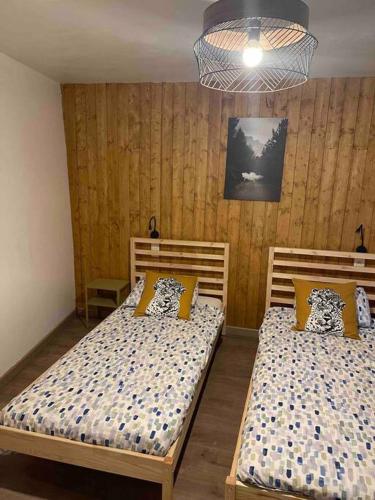 two beds in a room with wooden walls at B&B ArdennesT in Bouillon