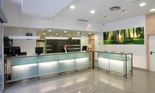 a woman standing behind a glass counter in a lobby at NH La Avanzada in Leioa