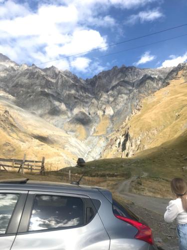 a woman standing next to a car looking at a mountain at Come & Rest in Stepantsminda