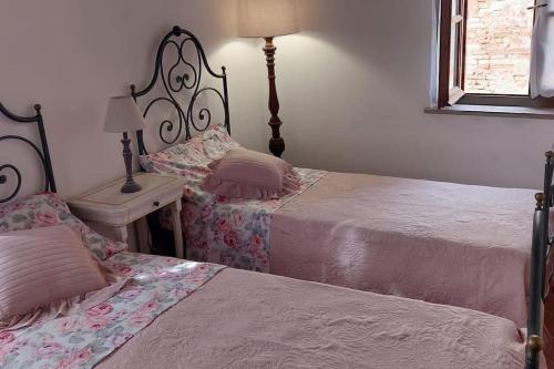 a bedroom with two beds and a table with a lamp at Lajatico Rentals - Casa di Alice nel Borgo in Laiatico