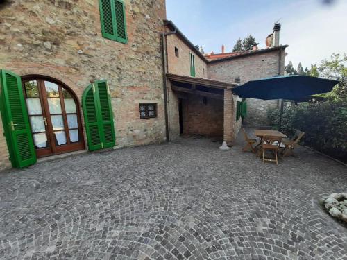 an outdoor patio with a table and an umbrella at Lajatico Rentals - Casa di Alice nel Borgo in Laiatico