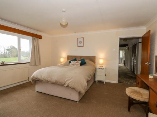 a bedroom with a bed and a desk and a window at Hawksbridge Bungalow in Macclesfield