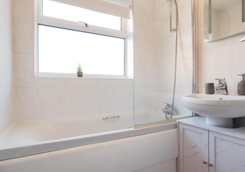 a bathroom with a tub and a sink and a window at Brigantine in Martham