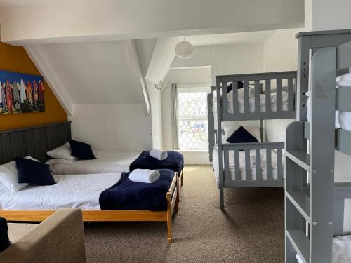 twee bedden in een kamer met twee stapelbedden bij Elemental Surf Lodge in Newquay