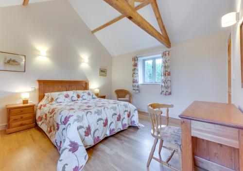 a bedroom with a bed and a wooden desk at Burtons Farm Barn 