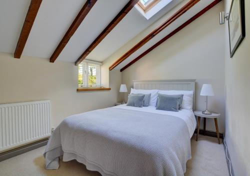 een slaapkamer met een groot wit bed op een zolder bij Bridge Cottage in North Creake