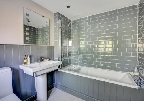 een badkamer met een wastafel, een bad en een bad bij Bridge Cottage in North Creake