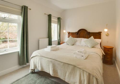 a bedroom with a large bed with towels on it at Brook Cottage in Dersingham