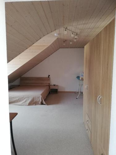 - une chambre mansardée avec un lit et un plafond en bois dans l'établissement Sonniges Fleckchen, à Griesheim
