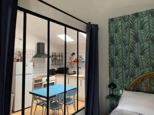 une chambre avec une table bleue et une cuisine dans l'établissement Charmant T2 très cosy au calme en hyper centre., à Rochefort