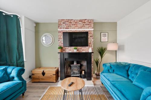 a living room with blue couches and a fireplace at Luxnightzz - Central 3 Bed House Parking in Colchester