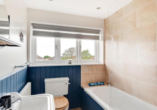 a bathroom with a tub and a toilet and a sink at Cherry Tree House in Sheringham