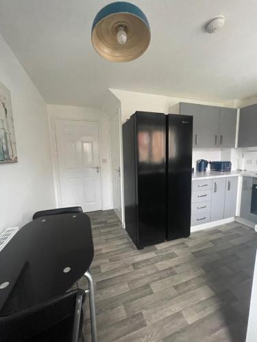 a kitchen with a black refrigerator and white cabinets at Baker House - Furnished Lets in Swinton