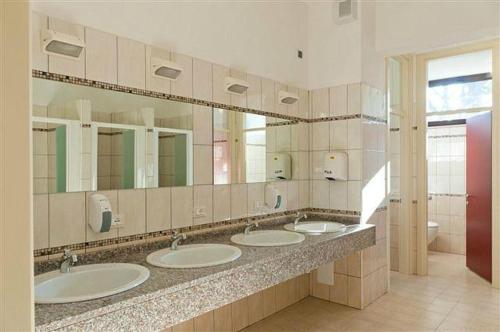 Baño con 4 lavabos y una fila de espejos en MiMa Hostel Moorea, en Milano Marittima