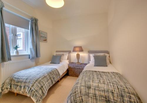2 camas individuales en una habitación con ventana en Corner Cottage en Cromer