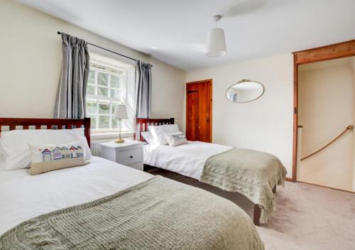 a bedroom with two beds and a window at Cuckoo Cottage in Blakeney