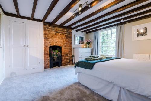 a bedroom with a large bed and a fireplace at Cheshire Countryside, Delamere Forest, Family Retreat Rose Cottage in Kelsall