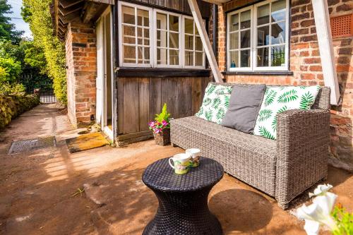 a wicker chair and a table on a patio at Cheshire Countryside, Delamere Forest, Family Retreat Rose Cottage in Kelsall