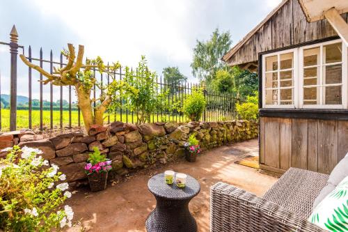 a patio with a stone wall and a table at Cheshire Countryside, Delamere Forest, Family Retreat Rose Cottage in Kelsall