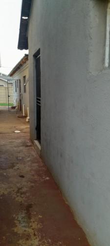 an empty alley with a white building and a door at Dawn Park Guest House in Boksburg