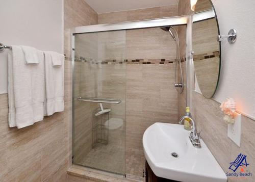 een badkamer met een douche, een wastafel en een spiegel bij Tropic Breeze 17 in St Pete Beach