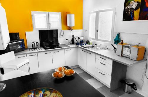 a kitchen with white cabinets and a bowl of oranges on the floor at LE CHERCHE MIDI Chambres d'hôtes avec CUISINE EQUIPEE grand jardin PARKING SECURISE GRATUIT in Albi