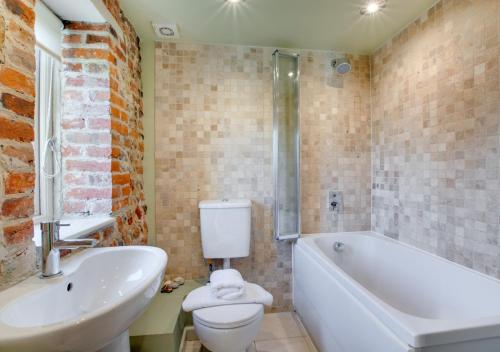 a bathroom with a tub and a toilet and a sink at Crossways Barn in Briston