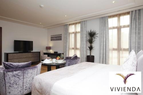 a bedroom with a bed and chairs and a television at Vivienda Hotel Villas Granada in Riyadh