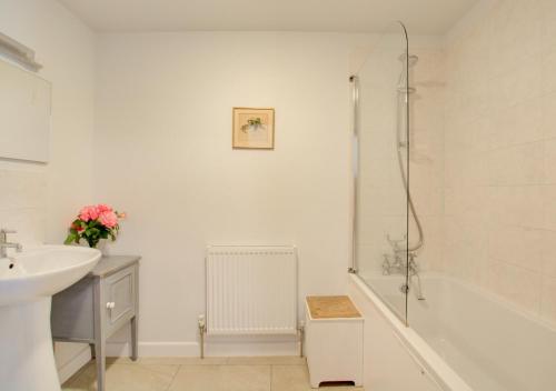 a white bathroom with a sink and a bath tub at Dockings Cottage in Hindringham