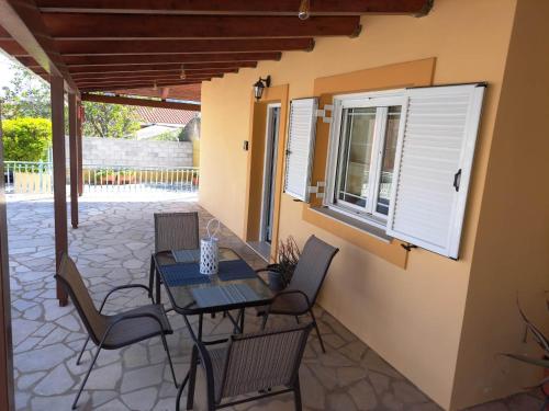 a patio with a table and chairs and a window at Casa di Dioniso in Valsamáta